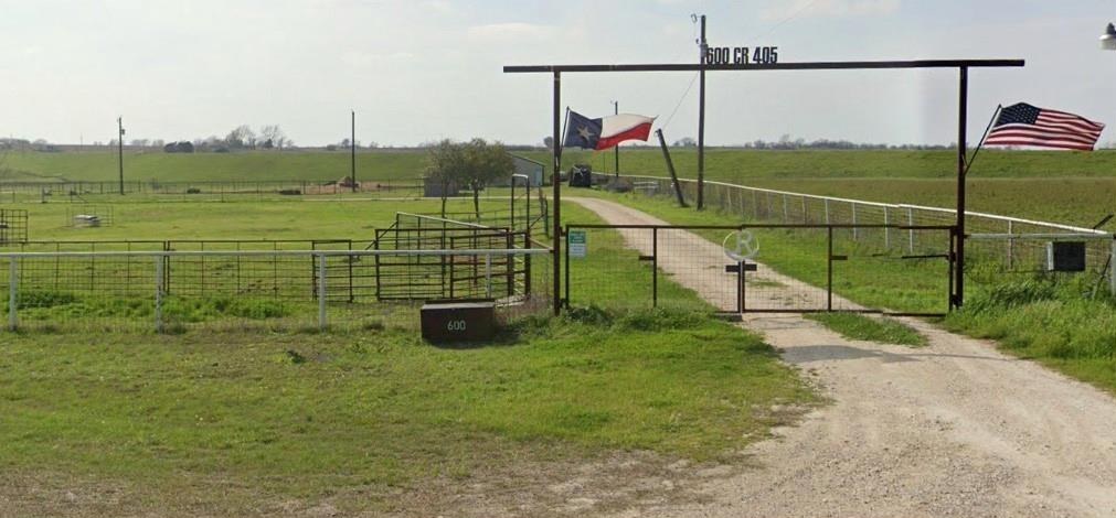 Pipe entry gate with the address 600 CR 405, a Texas flag and an American flag.