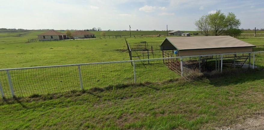 Covered livestock shelter and steel pens inside the fence line.